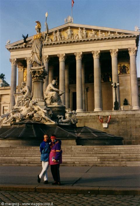 Two tourists pose by the Athena fountain and Vienna Parliament columns