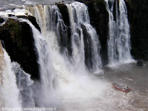 Iguazú Falls: walls of foaming water with a red tourist boat below