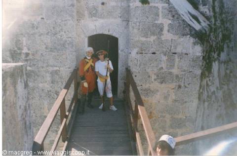 Two costumed guides on the wooden bridge of an old stone fortress