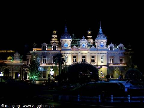 The Monte Carlo Casino lit up at night among palm trees and gardens