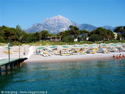Kemer beach with umbrellas, wooden pier and Mount Tahtalı in the background