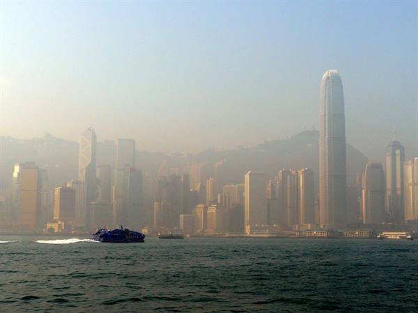 Fast ferry crossing the bay before skyscrapers in haze, Hong Kong
