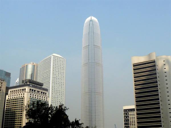 Hong Kong's IFC tower rises among glass skyscrapers under a blue sky
