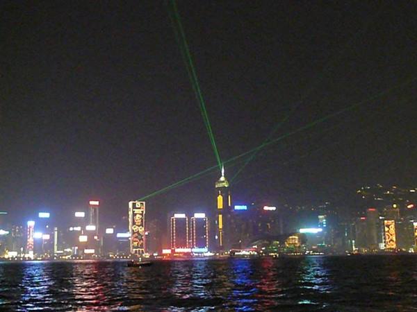 Green laser beams over Hong Kong skyline, skyscraper lights reflecting on the water