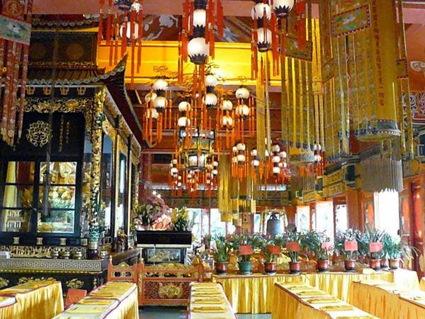 Buddhist temple interior with hanging lanterns, golden altars and set tables