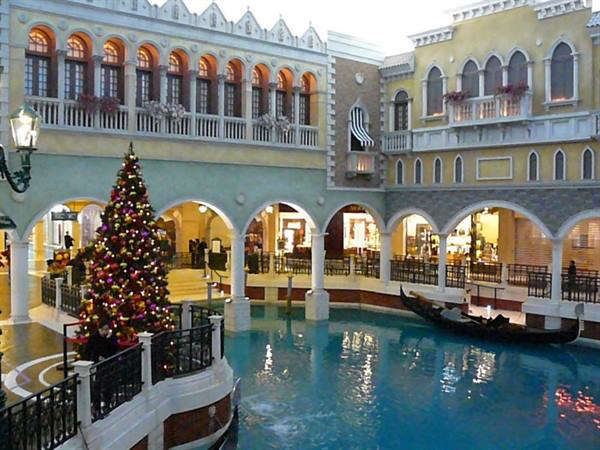 Decorated Christmas tree beside the canal with gondola under the arcades