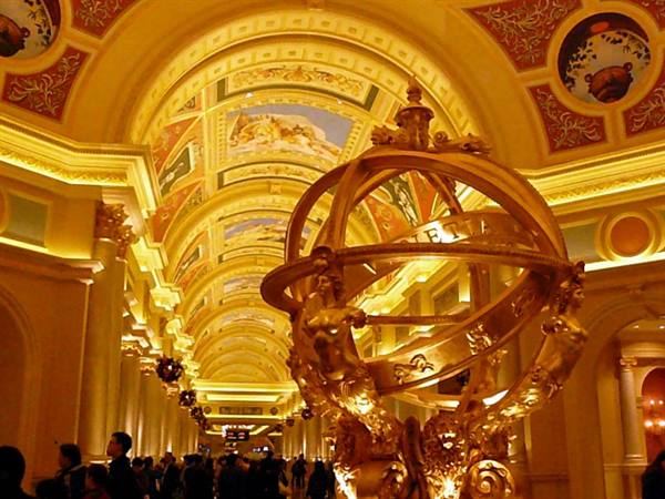 Golden armillary sphere in the Venetian's frescoed arcade, warm golden light