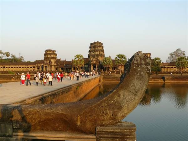 Angkor Wat: tourists crossing the stone causeway with naga balustrade