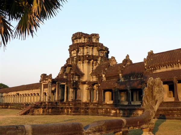 Sandstone tower of Angkor Wat with galleries and naga statue at dusk