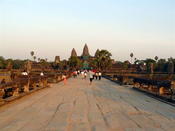 Tourists walk the stone causeway toward Angkor Wat towers