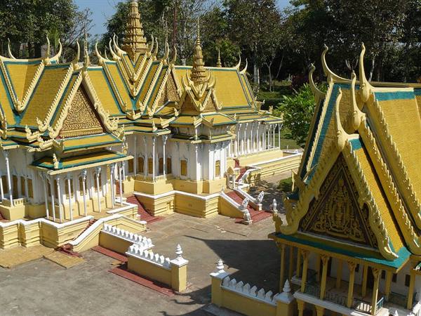 Golden roofs and spires of Phnom Penh Royal Palace among green trees