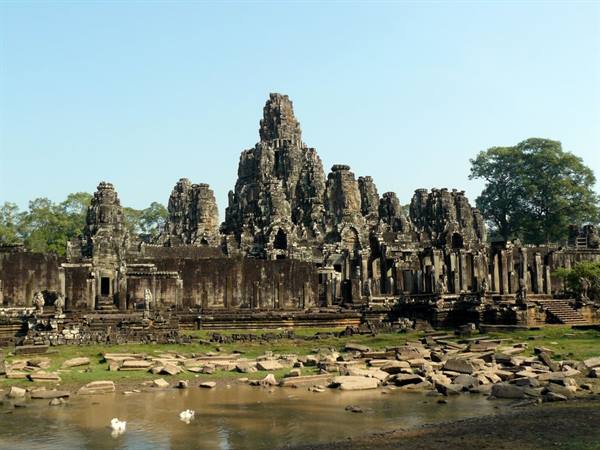 Stone towers of Bayon temple at Angkor Thom reflected in still water