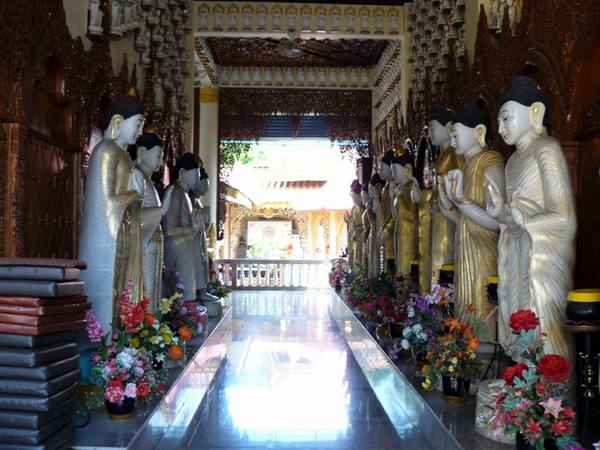 Rows of marble and gold Buddha statues lining a Burmese temple corridor