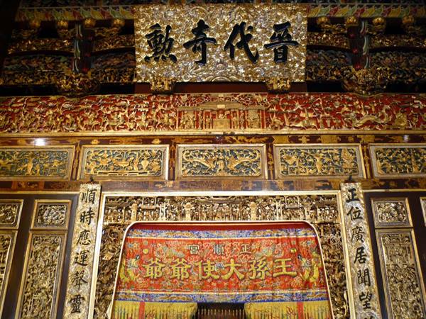 Temple interior with gilded carvings, calligraphy plaque and embroidered red altar cloth