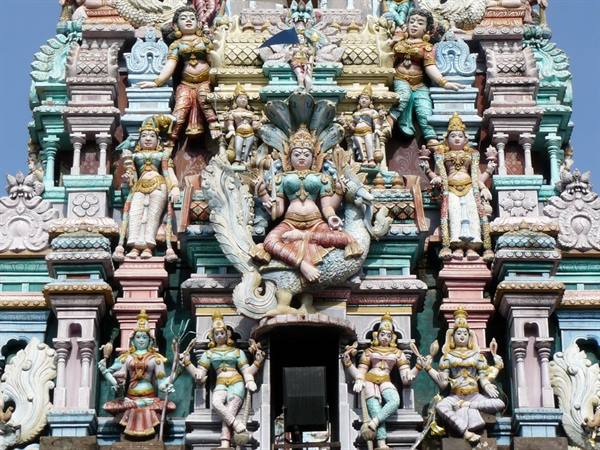 Hindu temple gopuram covered with colorful statues of deities and a goddess on a peacock