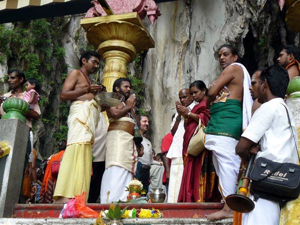 Devotees in dhotis pray inside Batu Caves, natural light