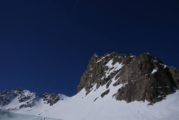 Snowy rocky peak against deep blue sky in high mountains