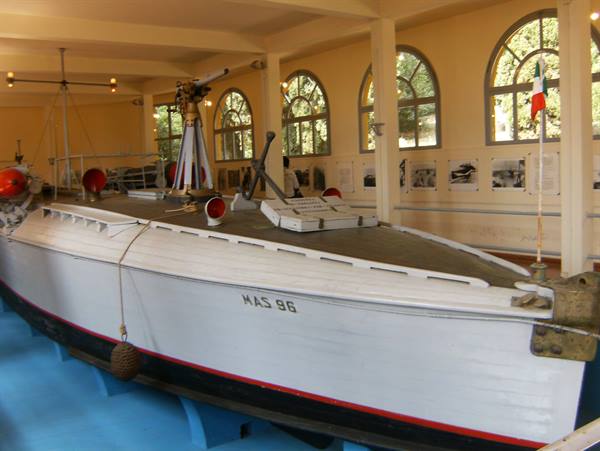 White and red MAS 96 displayed indoors with deck gun, Italian flag, arched windows