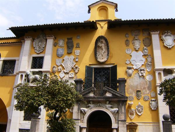 Yellow facade of the Vittoriale in Gardone Riviera with stone coats of arms and winged lions