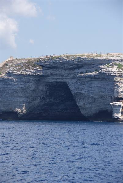 Tourists atop Bonifacio limestone cliffs above the blue sea