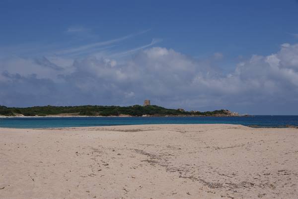 Pale sand before turquoise water, old tower on green headland