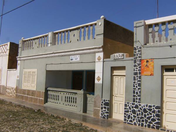 Grey and cream colonial houses with balustrade, BAR sign, blue sky