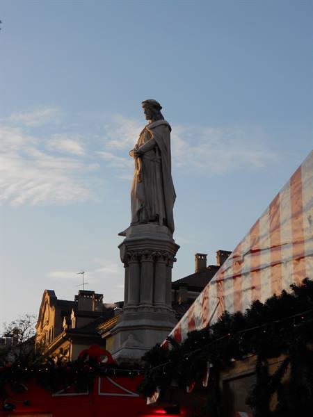 Marble statue of Walther von der Vogelweide in Bolzano, with Christmas market stall