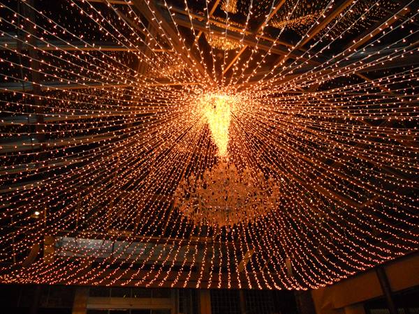 Crystal chandelier surrounded by thousands of golden string lights radiating outward