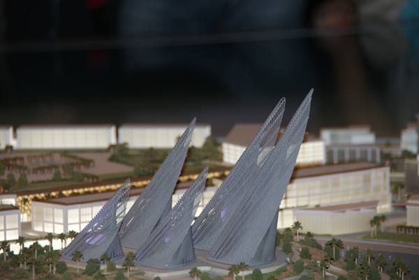 architectural model of gray sail-shaped towers among lit buildings