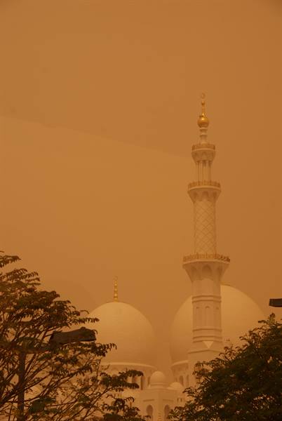 White minaret and domes of the Grand Mosque shrouded in dust
