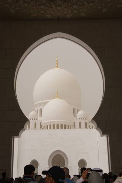 White dome of Sheikh Zayed Grand Mosque framed by an arch