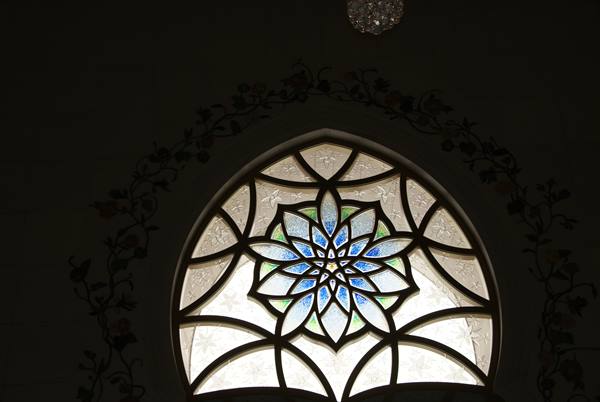 Arched window with blue stained-glass rosette, backlight glowing through