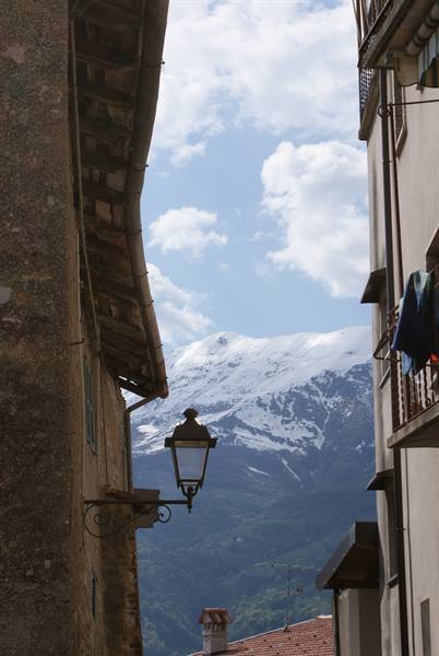 Iron lantern in narrow alley between old houses, snowy mountain behind