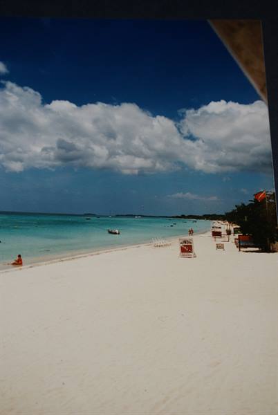 White sand beach with loungers, chairs and boats on turquoise water