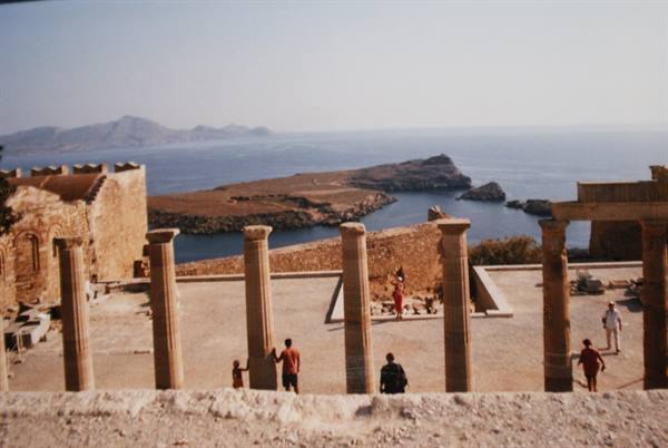 Ancient columns of Lindos acropolis overlooking the sea with tourists