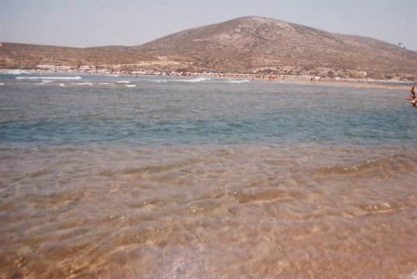 Clear shallow water and gentle waves in front of a dry hill and beach