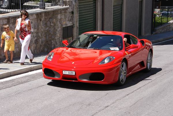 Red Ferrari parked along the street, mother and child walking on the sidewalk