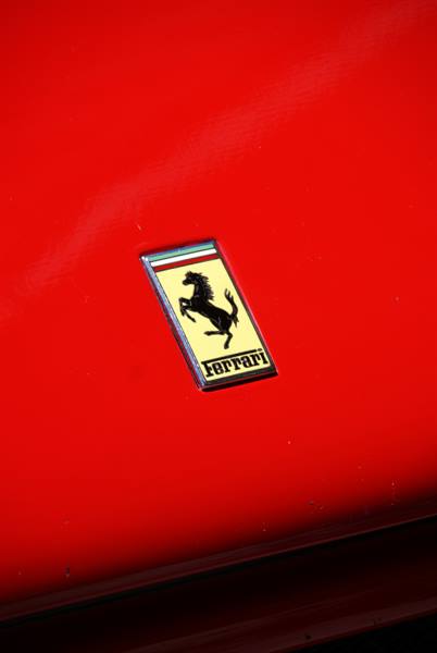 Ferrari prancing horse badge on glossy red car body