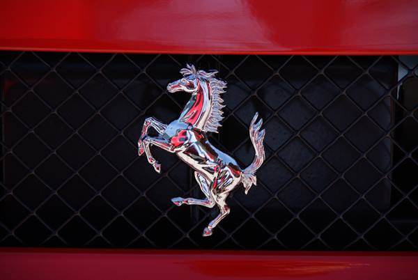 Chrome prancing horse badge on the black grille of a red Ferrari