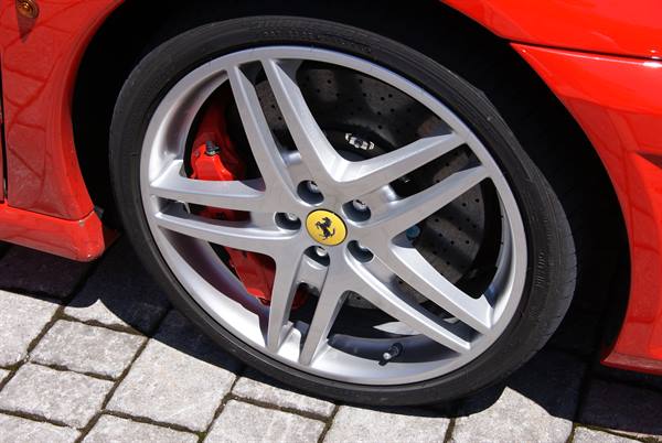 Silver five-spoke alloy wheel with Ferrari badge on red bodywork