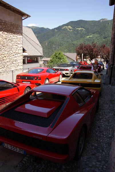 Red and yellow Ferraris parked on cobblestones in a mountain village