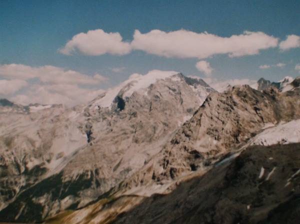 Snow-capped rocky peaks under a blue sky with white clouds