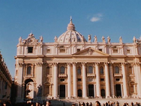 St Peter's Basilica facade in Rome, statues and columns under blue sky