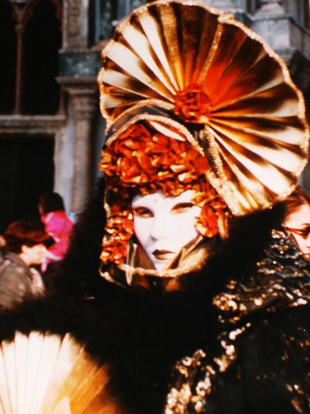 Venice carnival masker with white face and golden fan-shaped headdress