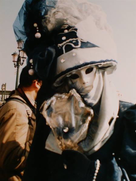 White mask with blue hat at Venice Carnival, sunlight