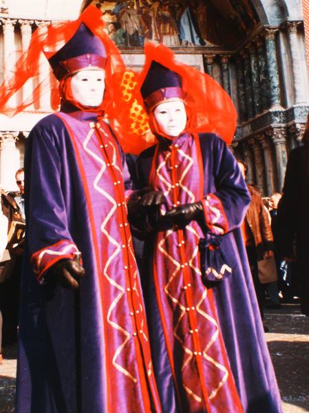 Two figures in purple velvet and red veils pose in St Mark's Square, Venice