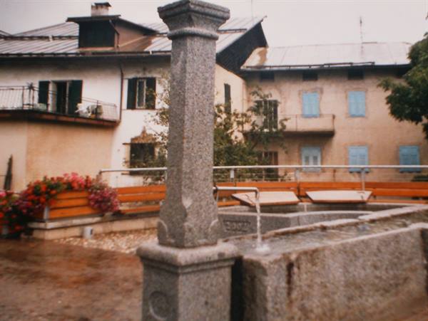 Stone fountain with column and running water in rainy village square