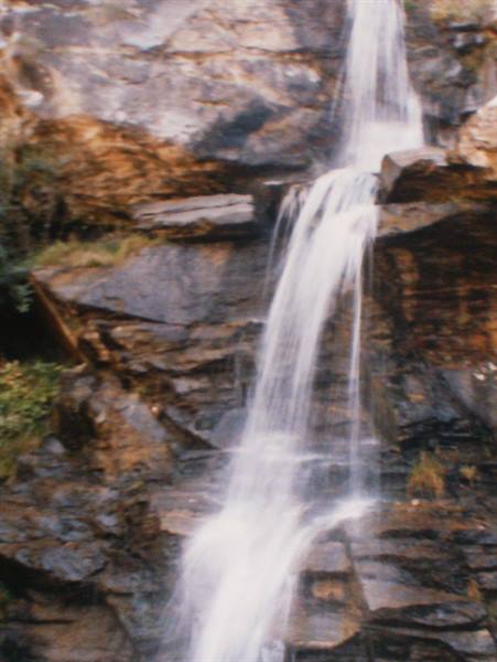 White waterfall cascading down dark wet rocks