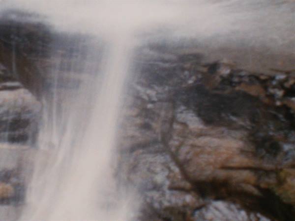Blurry waterfall streaming over dark wet rocks
