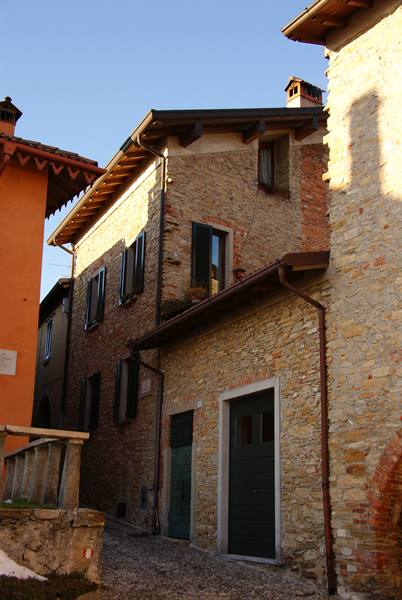 Stone row houses with wooden roofs, morning light on cobbled lane
